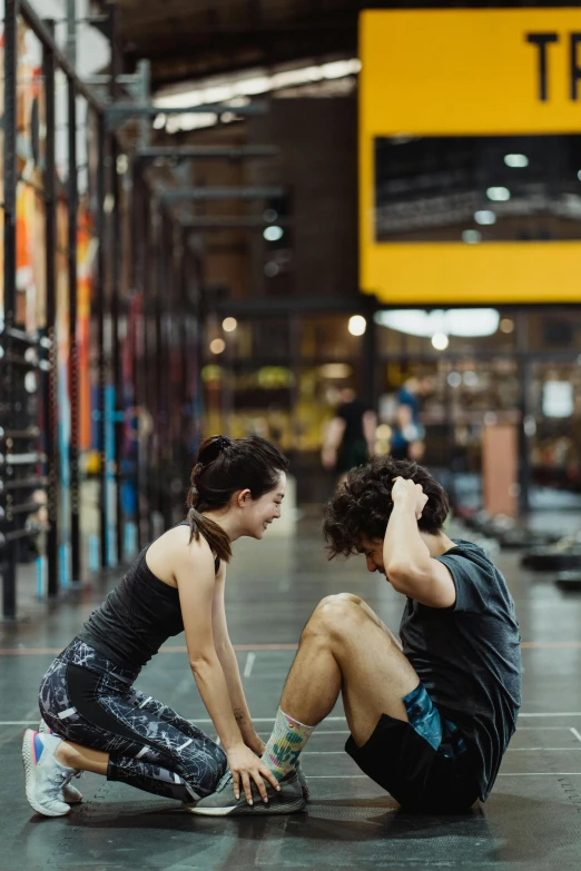 two young people are sitting down on the floor at a warehouse