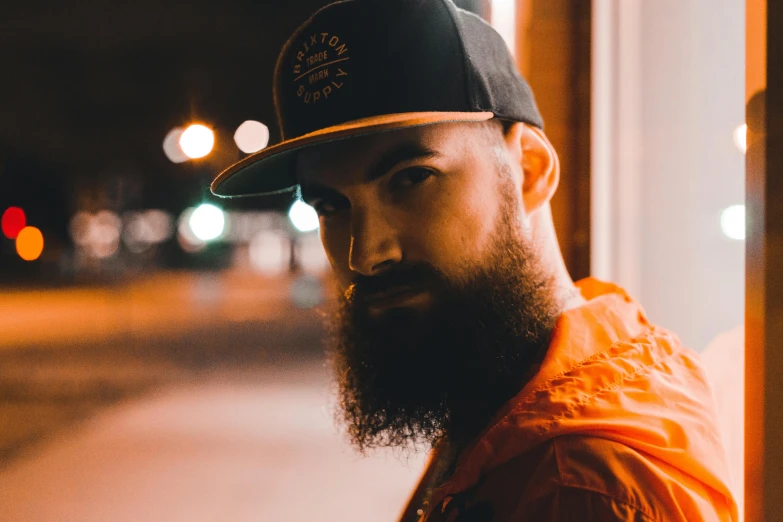 a man with long beard wearing a hat standing on the street