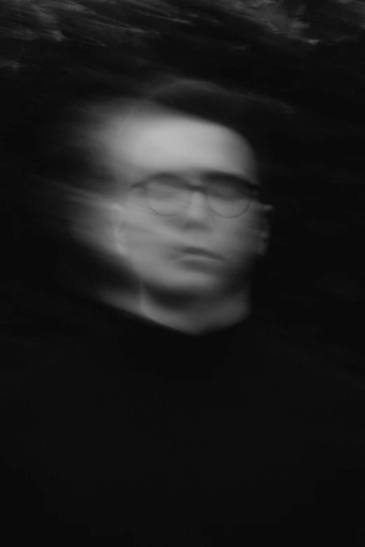 a blurry po shows a man wearing glasses and staring ahead