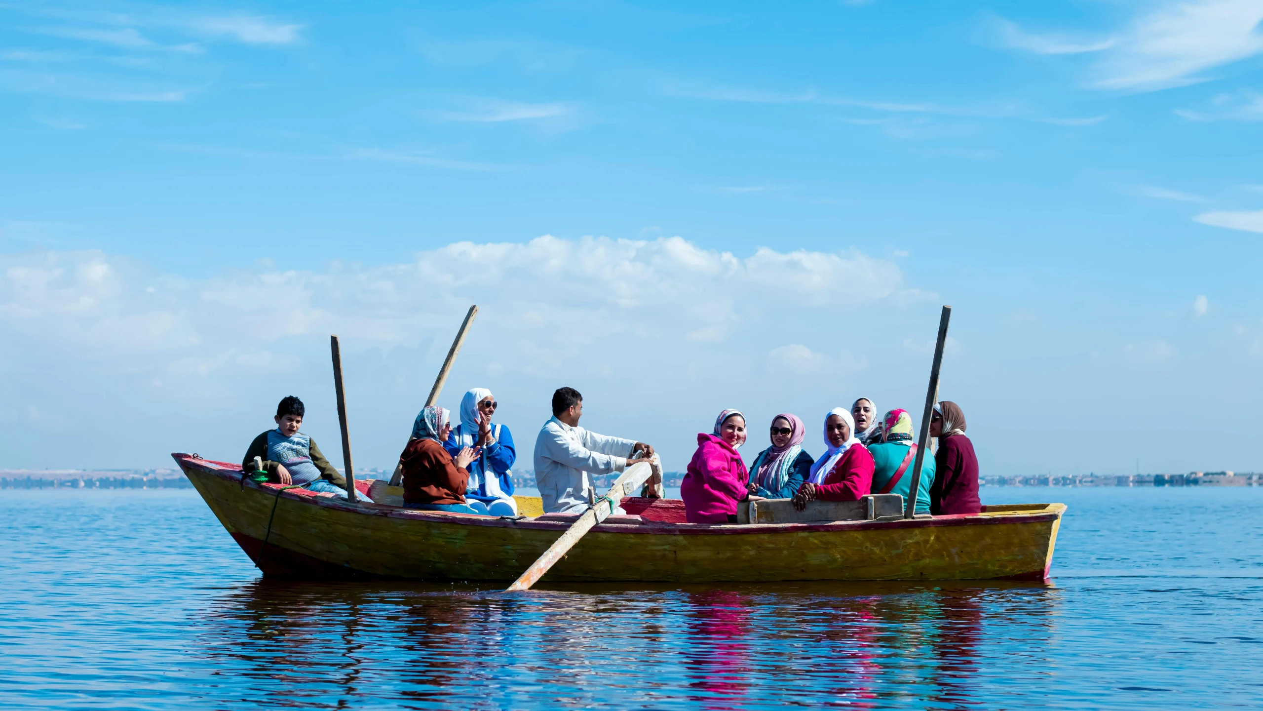 many people sitting in a small boat with poles