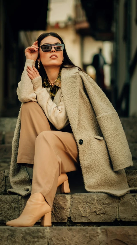 a woman with black sunglasses is sitting on the steps