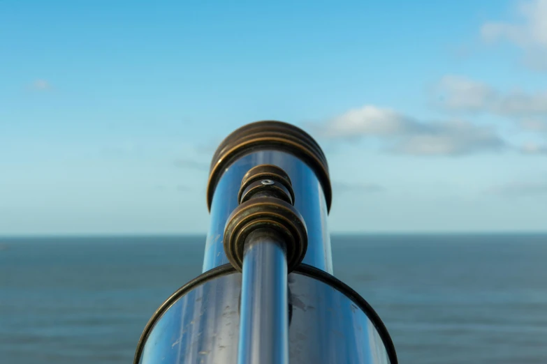 a metal pipe sticking out of the side of a hill next to the ocean