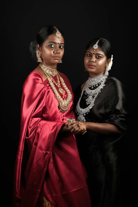 two women dressed in indian garb pose for a pograph