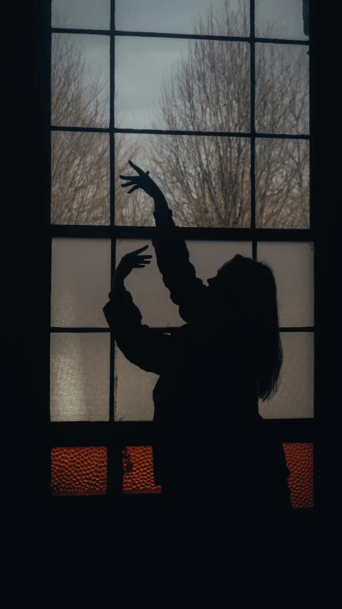 a person pointing at soing in front of a window