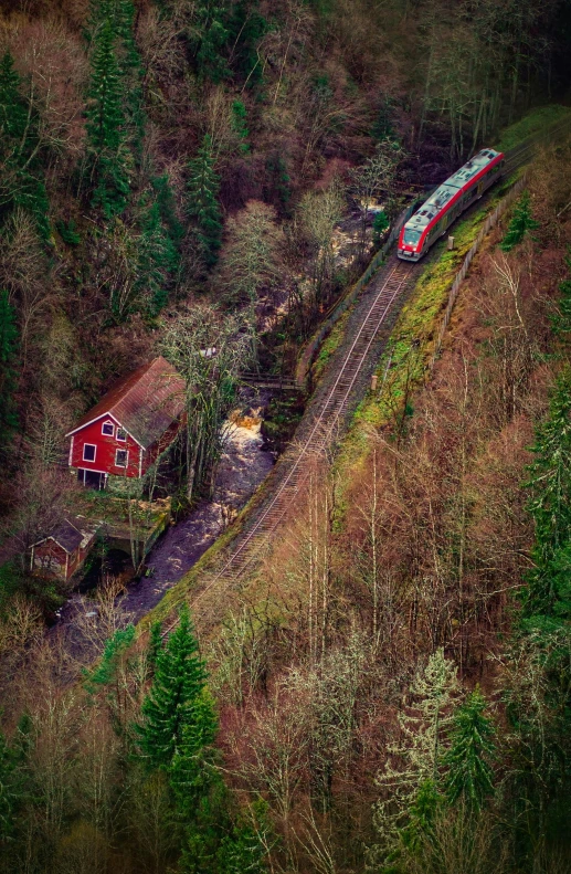 an aerial view of a train traveling along tracks near a forested area