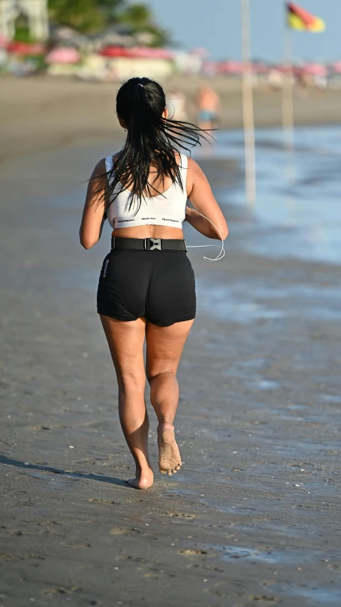 a woman running along the beach in high shorts