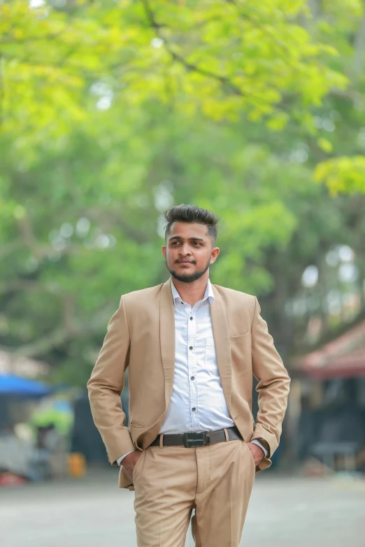 a man standing in front of a tree and wearing a suit