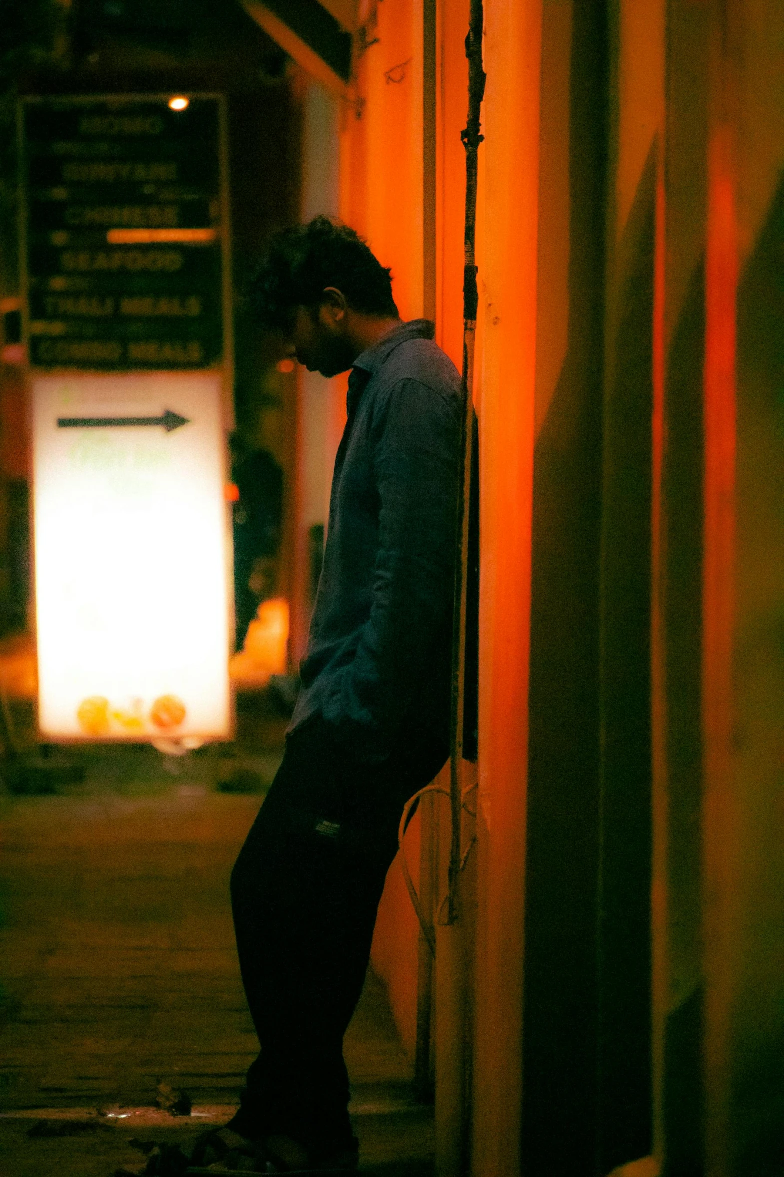 a person stands against a wall near a skateboard