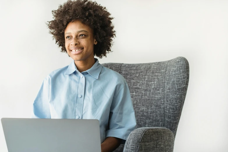 a woman sitting in a chair working on a laptop