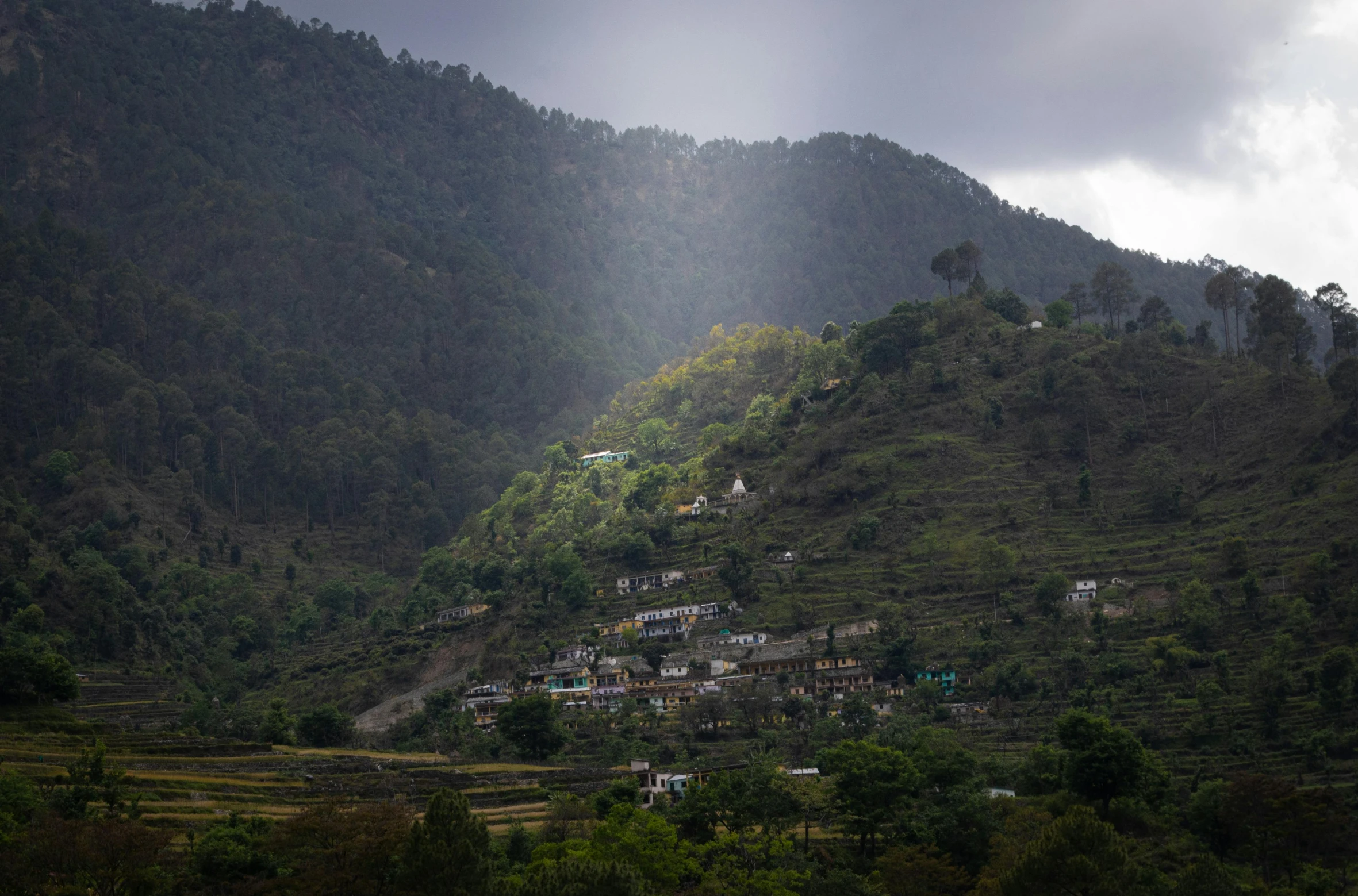 some buildings on the side of a green hill