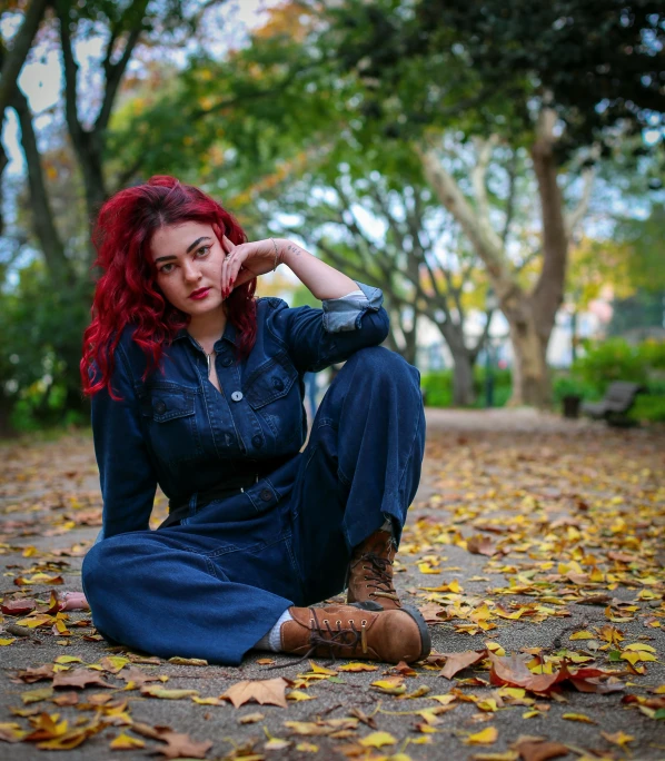 the woman is sitting on the ground near some leaves