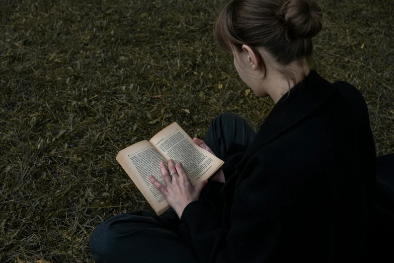 a woman reading a book outside on the grass