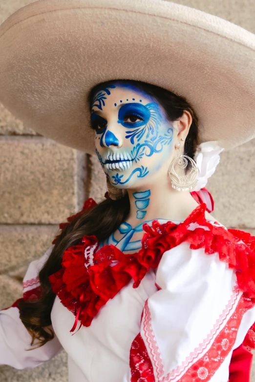 a woman wearing a mexican themed costume with white make - up and blue makeup