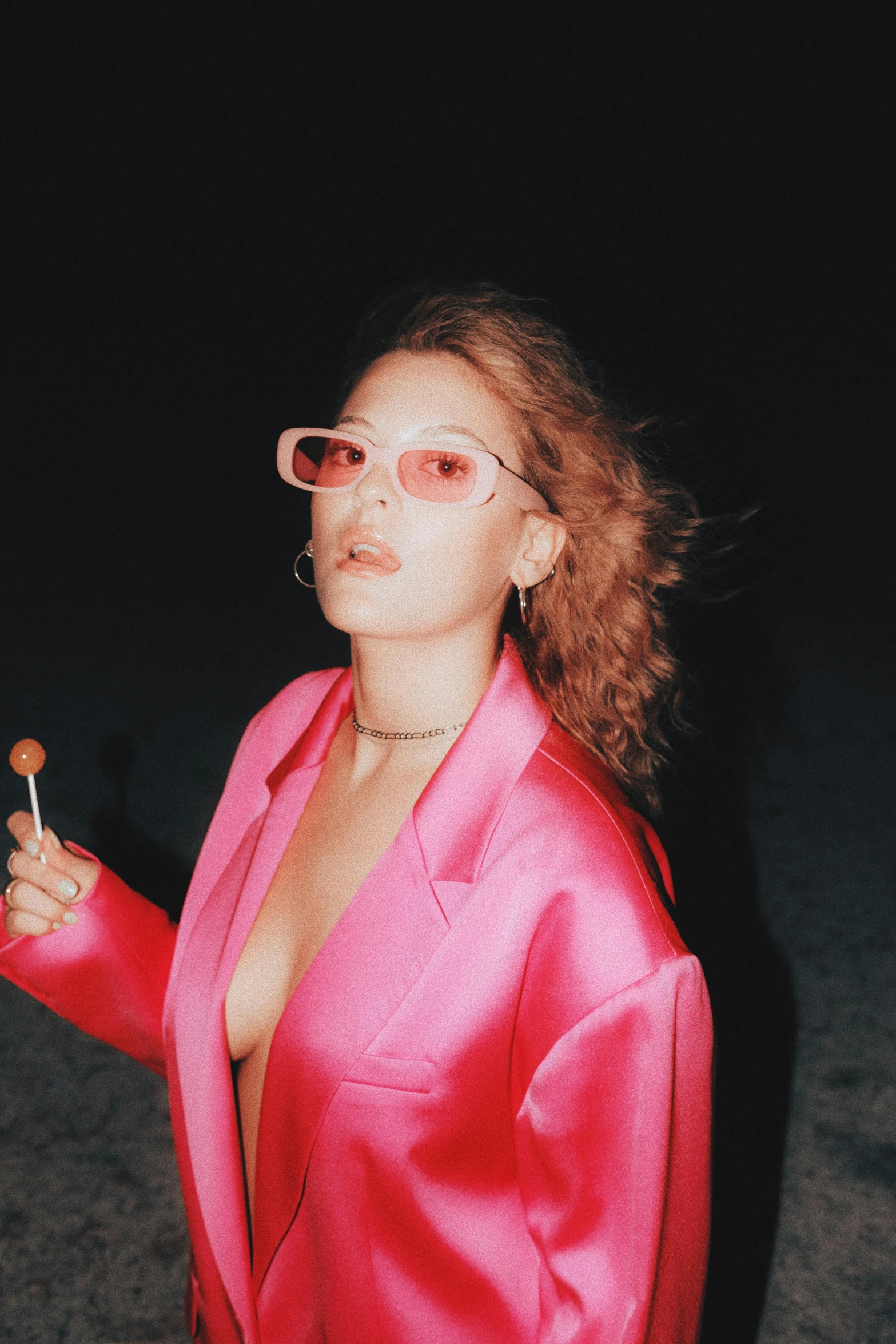 a woman wearing a pink suit and holding a cigarette