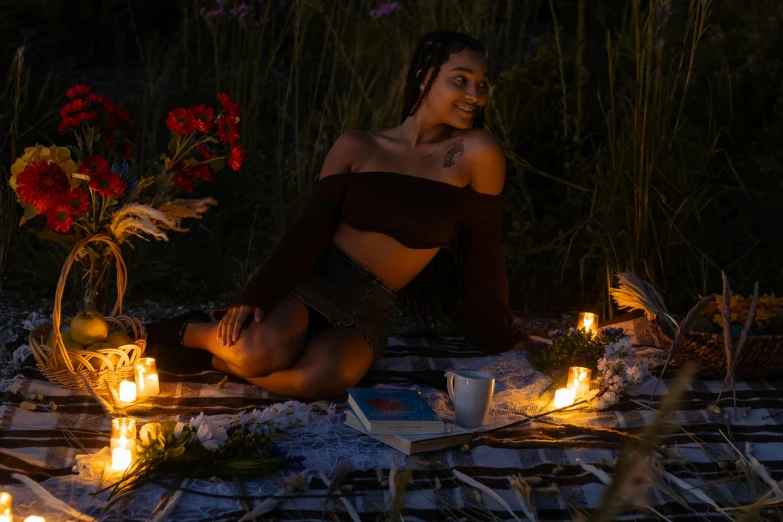 the woman is wearing a bikini while sitting on a blanket with lit candles around her