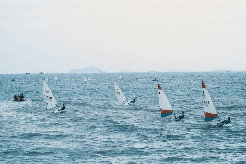 several sail boats in the ocean with people on board