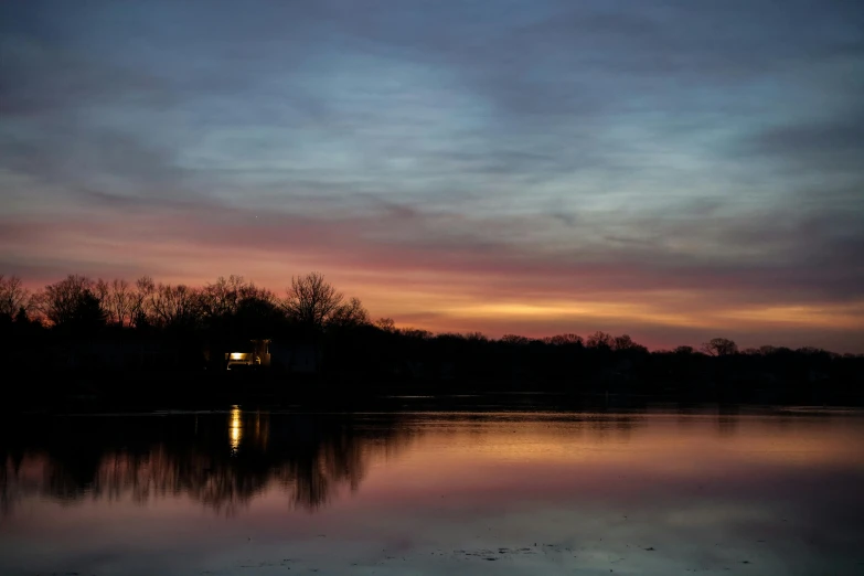 a lake and trees during the evening, with water reflecting the sky