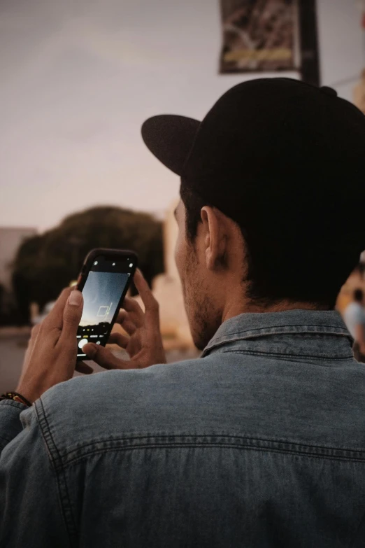 a man with a hat is looking at a cell phone