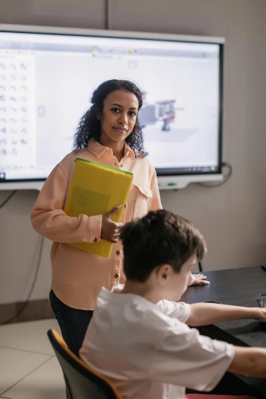 a woman is talking to a boy in front of a monitor