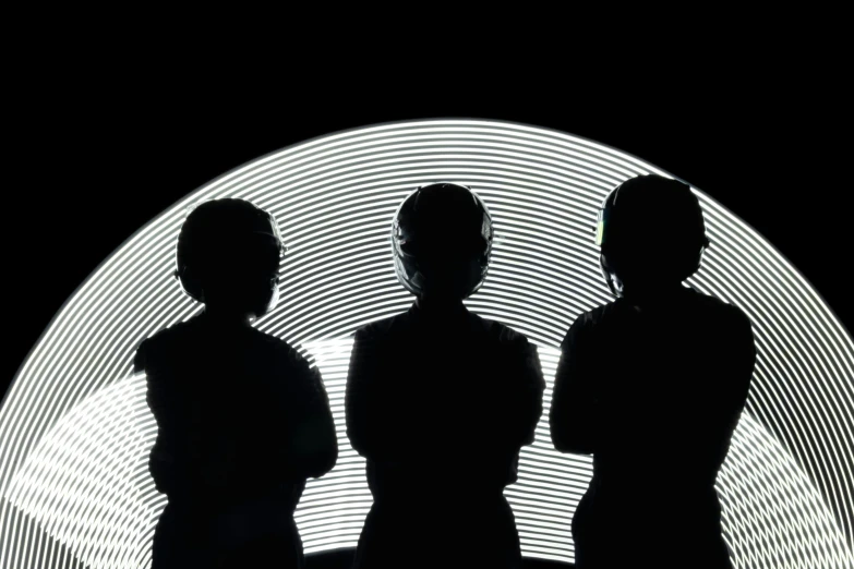 three people are standing in front of a circular black light