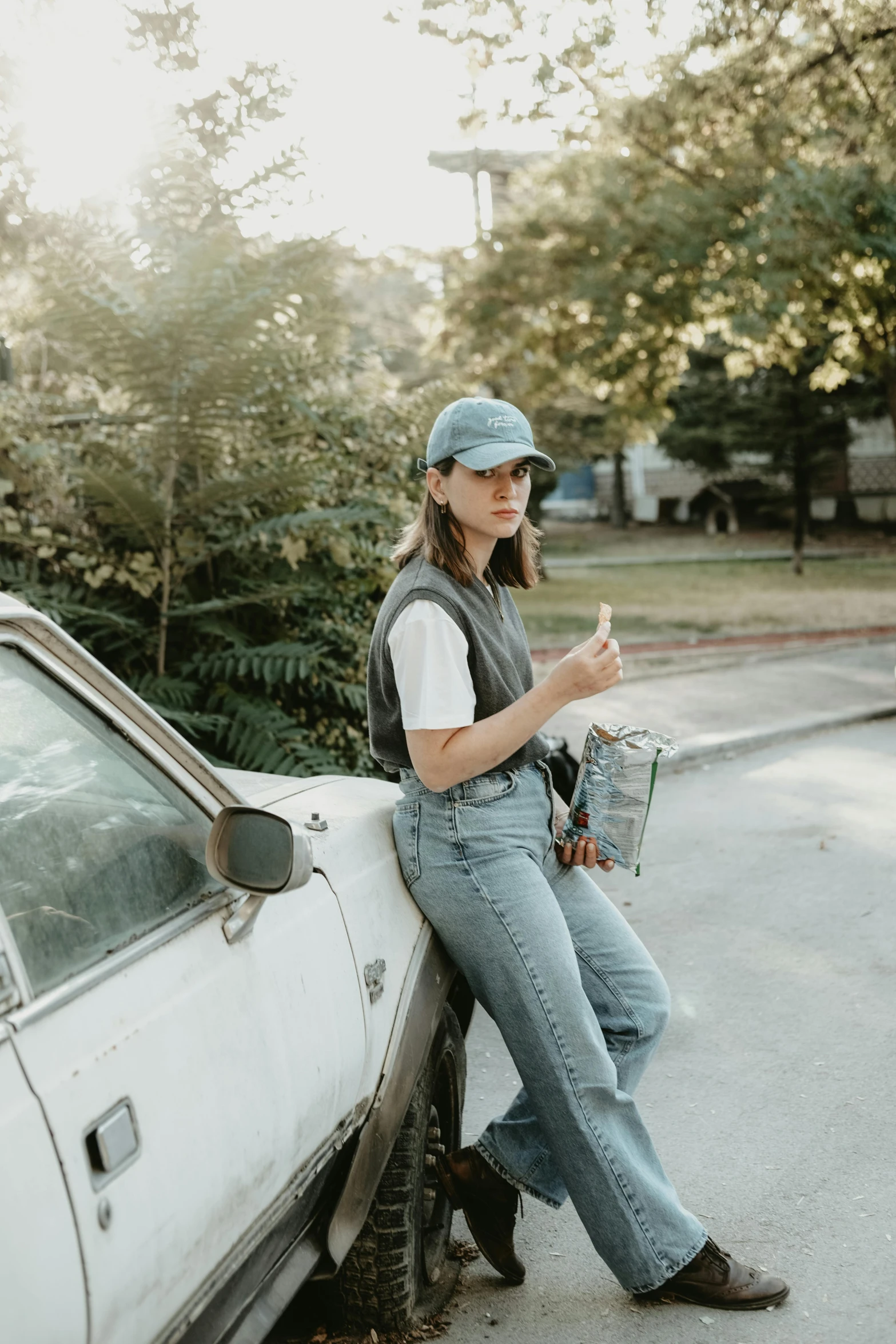 a woman sitting next to a car in the street