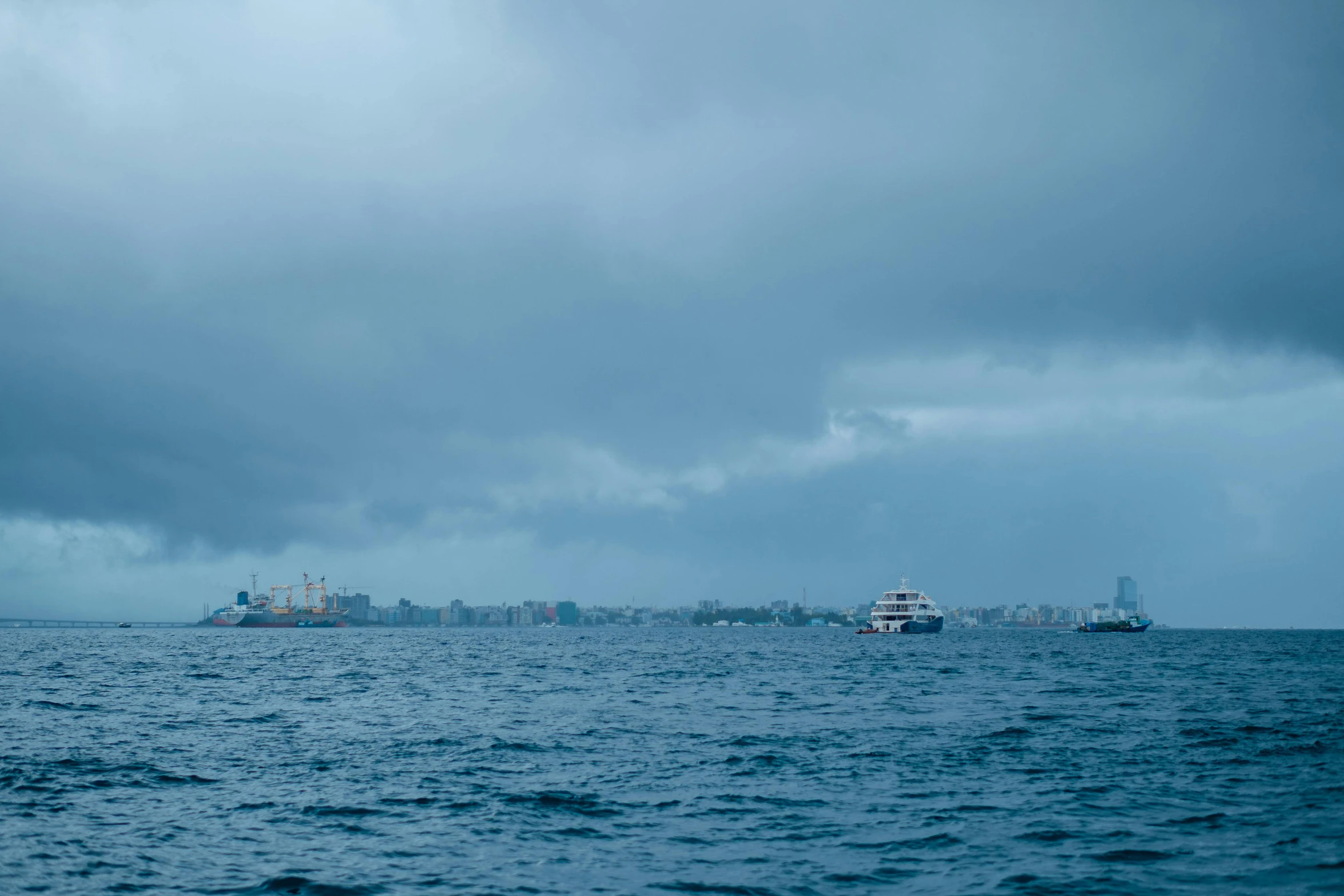 several ships out in the ocean on a cloudy day