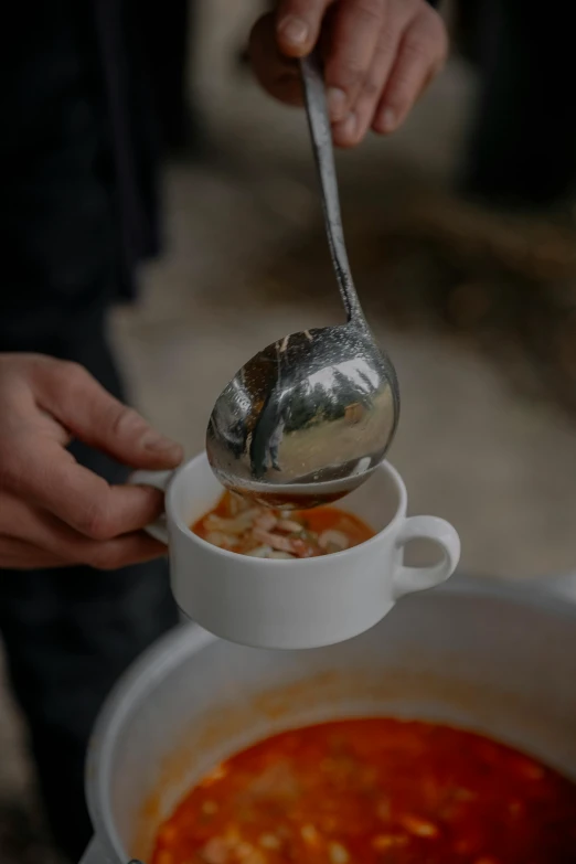 a man that is pouring soup into a cup
