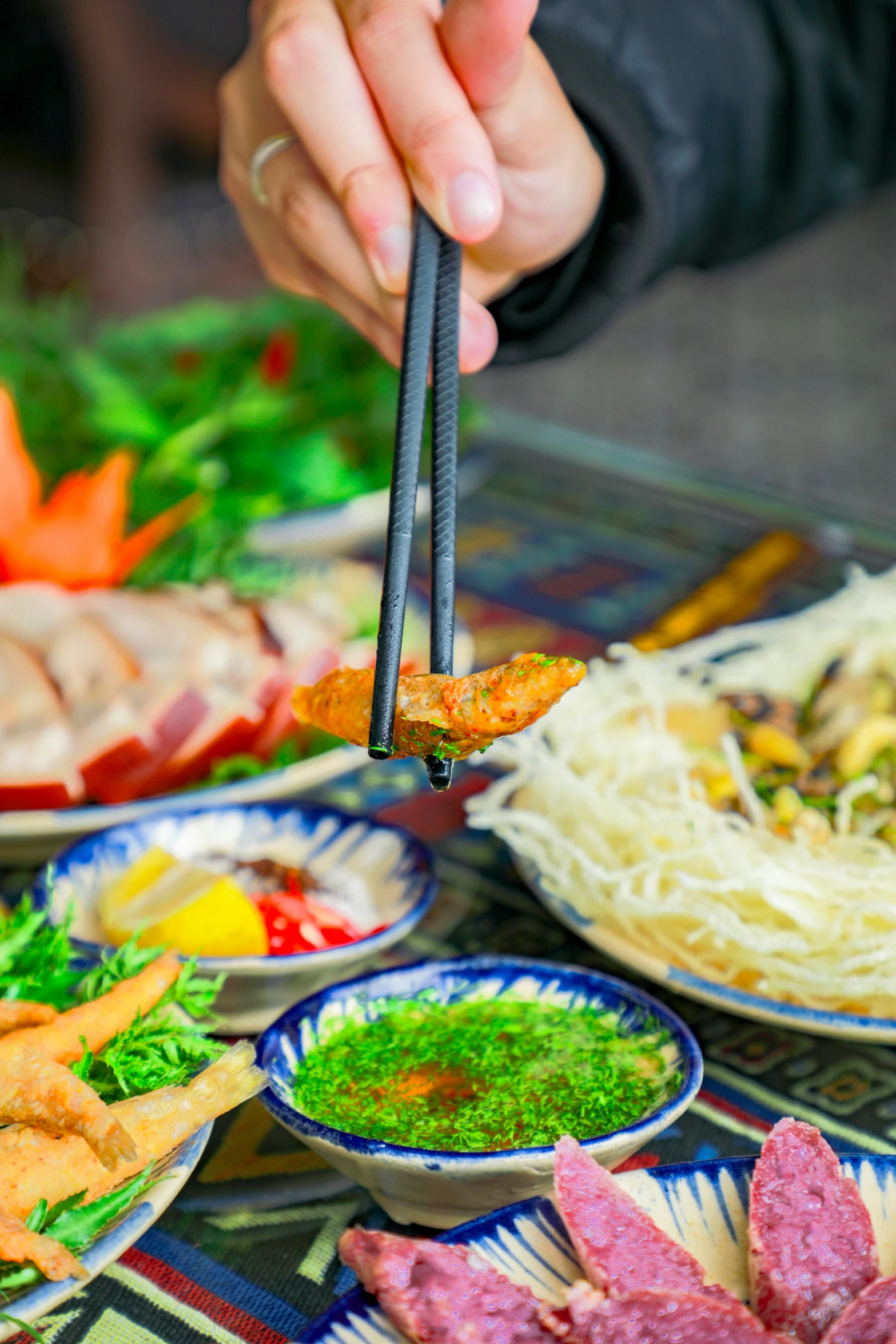 a person holding chopsticks to some meat on top of a plate