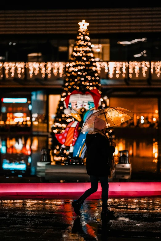 a man walking under a christmas tree in the rain