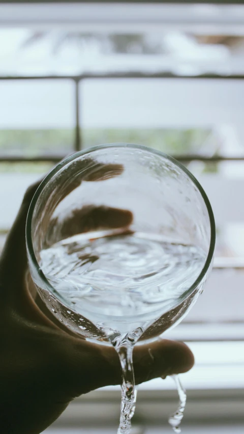 a hand is holding a small glass of water