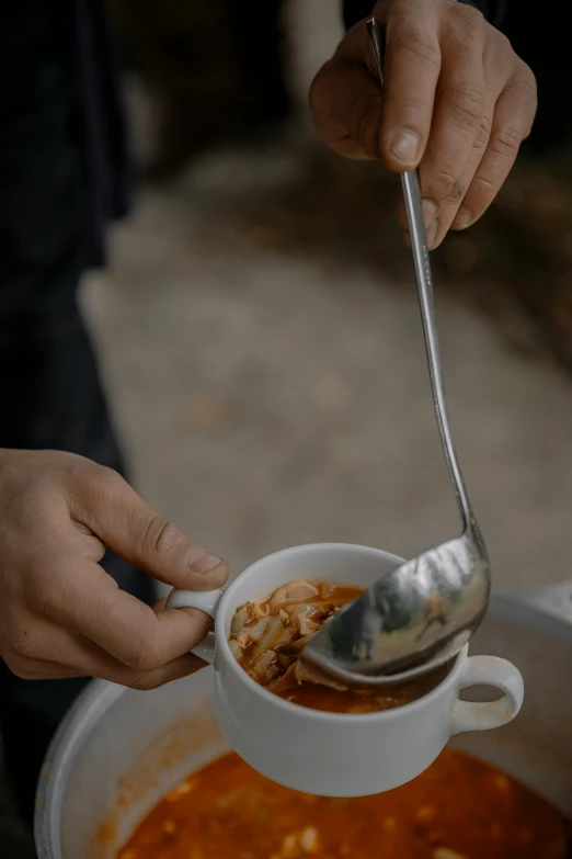 a bowl filled with soup and someone using a spoon