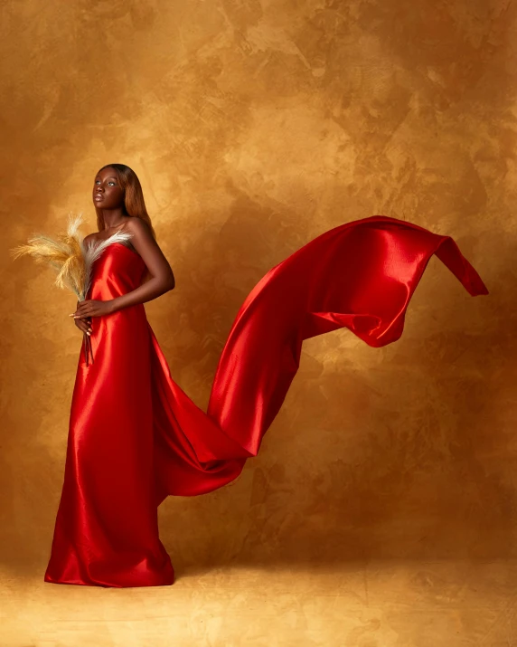 a woman with a red flowing dress posing for a po