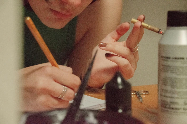 a young woman with a cigarette is writing on the paper