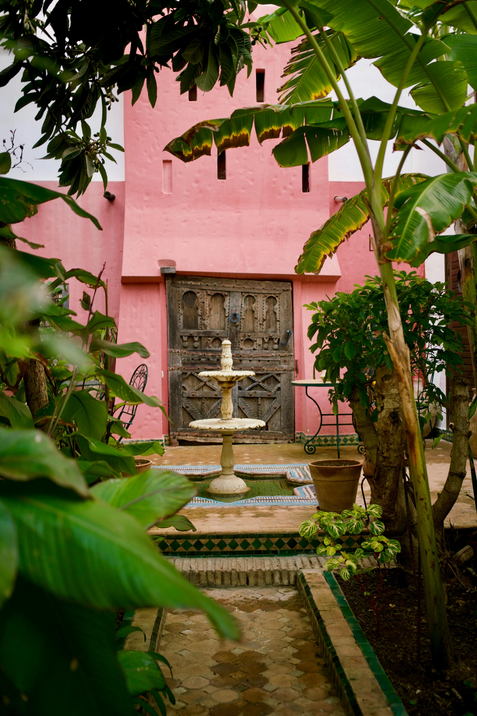 there is a pink house with trees and a fountain