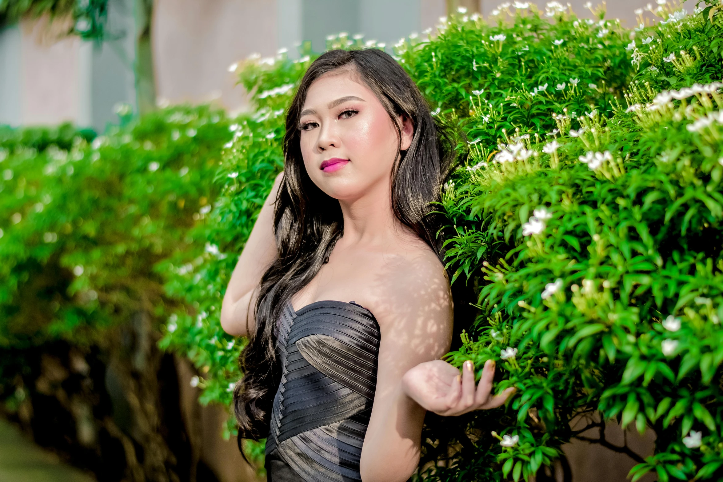 a woman poses by some green plants with pinkish cheeks