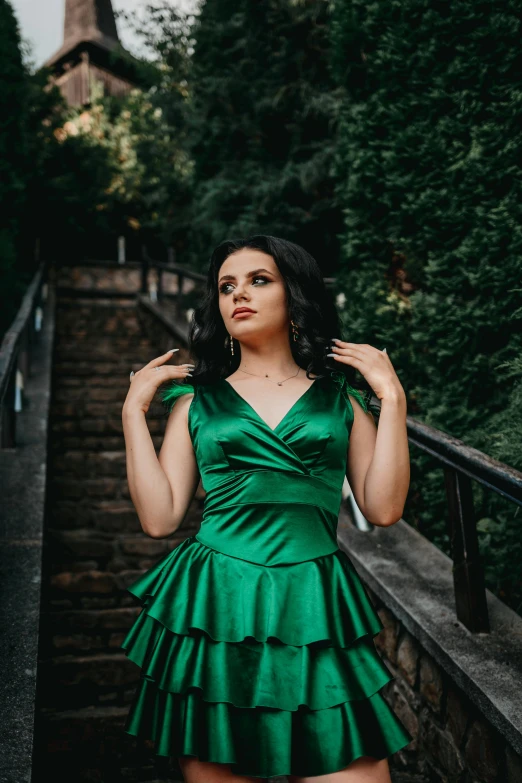 a woman in green poses on stairs near some steps