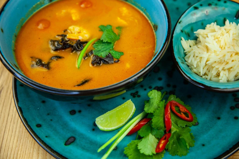 a blue bowl filled with soup and another dish of rice