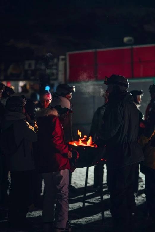 group of people standing next to fire pit with lights on