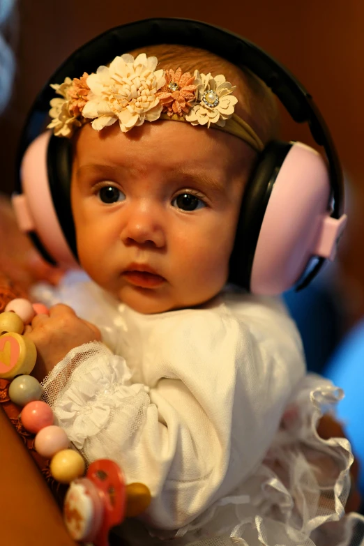 baby with headphones sitting on table with a pacifier