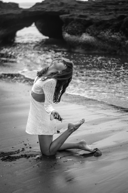 a pregnant woman kneeling in the sand at the beach