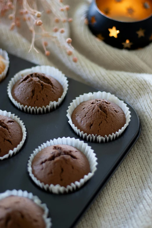 chocolate cupcakes on a tray near a candle