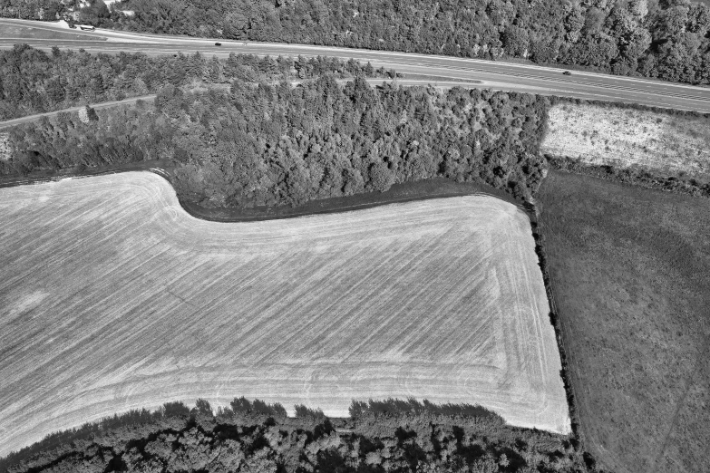 aerial view of a field and road with trees in the background