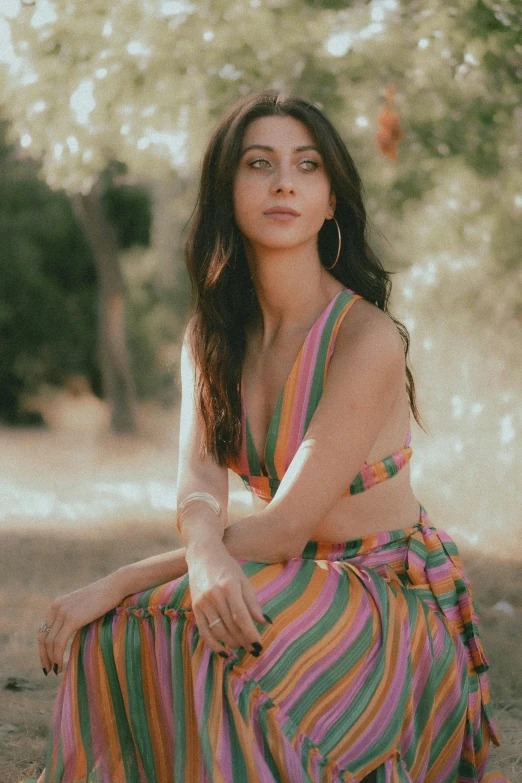 a woman is sitting on the ground, she looks very pretty