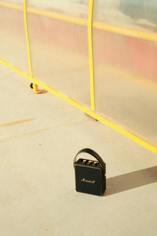 the suitcase is sitting next to the yellow fence