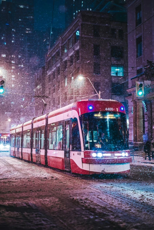 a train traveling down a snowy street during night