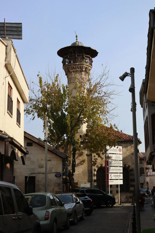 an old tower on top of a building with cars parked around it