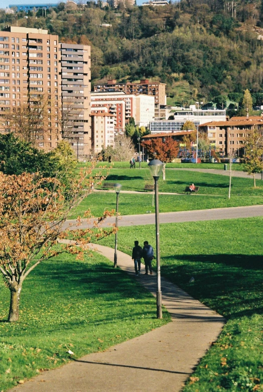 there are two people walking on the sidewalk in this park