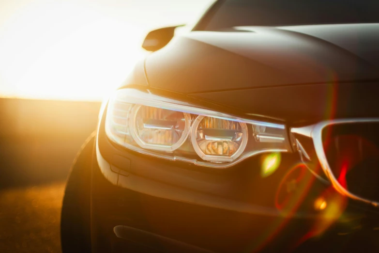 the front view of a bmw car with the sun shining behind it