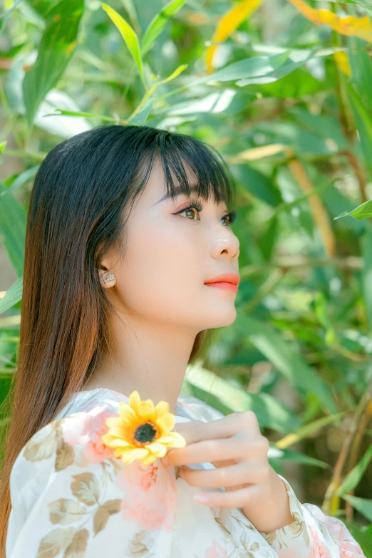 a young asian girl poses for the camera wearing an oriental - inspired dress and a flower in her left hand