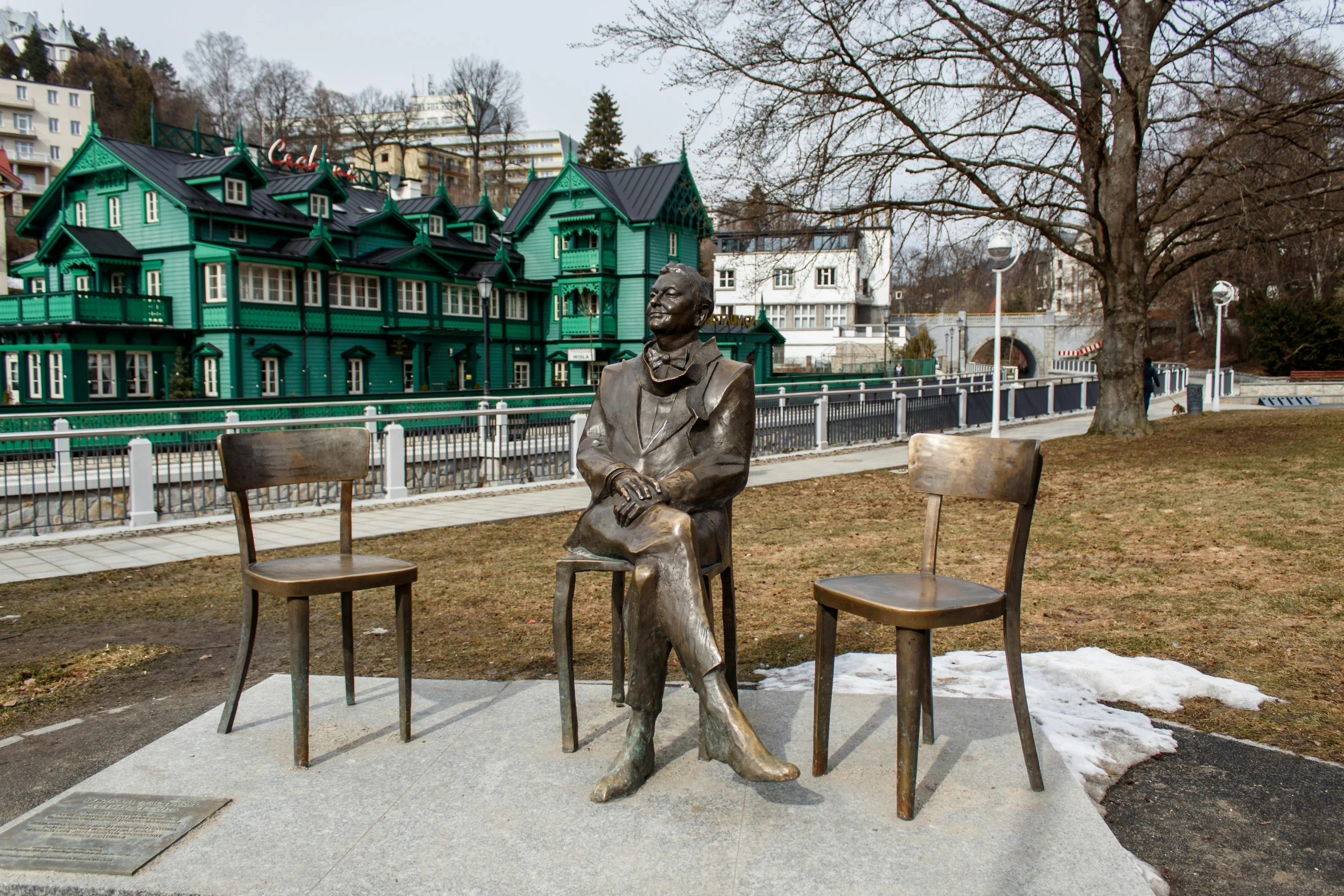 two chairs near a statue of a man sitting on the ground